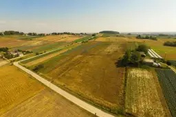 Widok z lotu ptaka na patchwork pól uprawnych, domy i szklarnie. Kto płaci podatek od dzierżawy gruntu? Rolnicy, którzy uprawiają te ziemie.