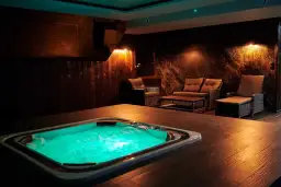 Wanna z zielonym podświetleniem i meble wypoczynkowe w przytulnym wnętrzu spa.
