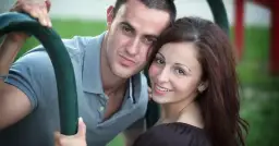 Para młodych ludzi, on w szarej koszulce, ona z brązowymi włosami, uśmiechnięci, widać ich związek z młodszym mężczyzną.