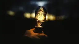 Dłoń trzyma żarzącą się żarówkę Edisona. Zastanawiasz się, ile to wat, gdy świeci 806 lumenów?