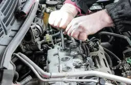 Mechanik wymienia świece zapłonowe w silniku samochodu.