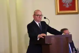 Mężczyzna w garniturze przemawia przy mównicy.