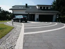 Nowoczesny podjazd z kostki brukowej, gdzie suchy beton pod kostkę tworzy idealne podłoże dla eleganckiego wzoru.