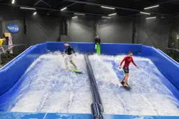 Ludzie surfują na sztucznej fali w Surf-Air, największym aquaparku w Polsce.