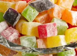 Kolorowe kostki galaretki w cukrze w szklanej misce.