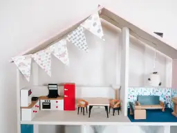 Uroczy domek dla lalek DIY z kuchnią, jadalnią i salonem. Girlanda z makaroników dodaje mu uroku.