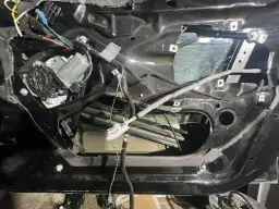 Wnętrze drzwi BMW E46 z widocznym mechanizmem podnoszenia szyby i przewodami.