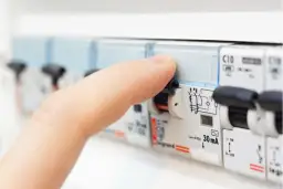 Palec dotyka wyłącznika w skrzynce z bezpiecznikami. Zastanawiasz się, jaki bezpiecznik do kuchni będzie najlepszy?