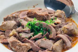 Duszona wątróbka drobiowa, idealnie ugotowana, by wiedzieć jak długo gotować wątróbkę drobiową. Podana z zieloną natką pietruszki.