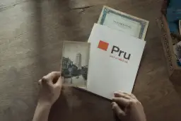 Ręce trzymają stare zdjęcie i dokument z logo Pru, part of M&G plc. To pokazuje, że Prudential to firma z długą historią.