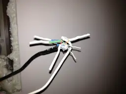 Przewody domofonowe w bloku, 6 żył. Widoczne gołe końcówki kabli, niebieski, zielony, czerwony i pomarańczowy.