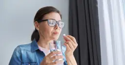 Kobieta w okularach bierze tabletkę, zastanawiając się nad mysimba skutki uboczne.