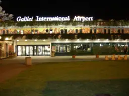 Port lotniczy Piza nocą. Jasny napis "Galilei International Airport" nad wejściem do terminalu.
