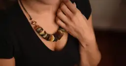 Kobieta w czarnej bluzce nosi naszyjnik z bursztynu.