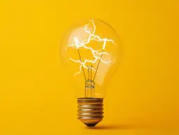 Żarówka z błyskawicami w środku na żółtym tle.