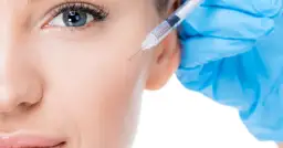 Zbliżenie na twarz kobiety z igłą strzykawki wstrzykującą botoks w skórę.