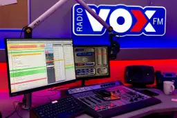 Studio radiowe VOX FM z mikrofonem, konsolą mikserską i monitorami.