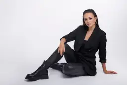 Elegancka kobieta w czarnym garniturze i spodniach woskowanych, prezentująca stylowe, nowoczesne stylizacje.