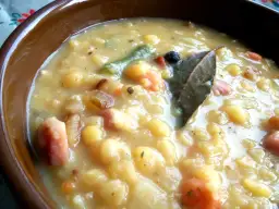 Gęsta zupa grochowa z kawałkami mięsa i warzywami w brązowej misce.