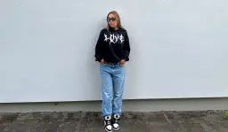 Dziewczyna w czarnej bluzie z kapturem i jeansach, idealny outfit, jak się ubrać na koncert hip hopowy.