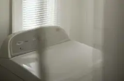 Górna część białej pralki ładowanej od góry z panelem sterowania.