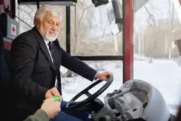 Starszy kierowca autobusu w garniturze odbiera bilet. Zastanawiasz się, ile zarabia kierowca autobusu?
