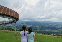 Dwie dziewczynki podziwiają malownicze góry sowie z tarasu widokowego.