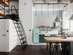 Industrialna kuchnia z miętową lodówką i drewnianym blatem. Czarne kable na suficie tworzą ciekawy element dekoracyjny.