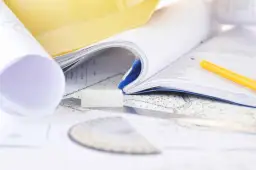 Plany, notatnik, ołówek i linijka na mapie.