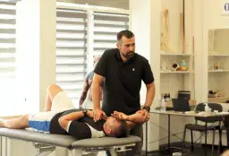 Fizjoterapeuta wykonuje badanie pacjenta na kozetce, ćwicząc diagnozę różnicową.