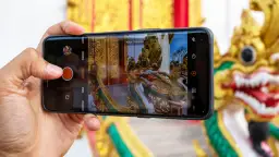 Dłoń trzyma smartfon, na ekranie którego widać smoka i złote zdobienia. Tak właśnie można zacząć przygodę, jak zrobić dobre zdjęcie telefonem.