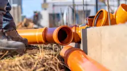 Pomarańczowe rury kanalizacyjne na budowie. Sprawdź przyłącze wod kan cennik dla Twojej inwestycji.