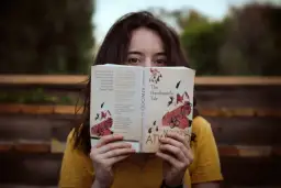 Dziewczyna w żółtej bluzce czyta książkę po angielsku "The Handmaid's Tale" Margaret Atwood.
