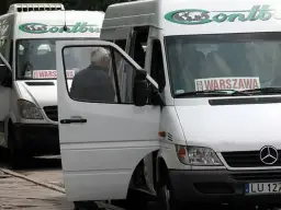 Białe busy Contbus z napisem "WARSZAWA" na przedniej szybie, jeden z otwartymi drzwiami.