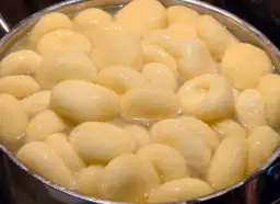 Kluski śląskie gotujące się w garnku z wodą.