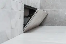 Otwarta klapka rewizyjna w łazience, pokazująca, jak zamontować drzwiczki rewizyjne plastikowe.