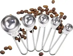 Zestaw metalowych miarek kuchennych z kawą w ziarnach.