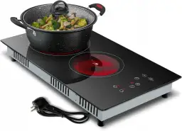 Płyta ceramiczna na 230V z wtyczką do gniazdka, gotowa do pracy. Garnek z warzywami na rozgrzanej płycie.