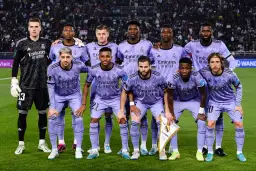 Drużyna pilkarze Real Madryt w fioletowych strojach pozuje do zdjęcia na murawie stadionu.