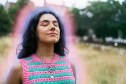 Kobieta z zamkniętymi oczami i kolorową aurą wokół głowy.