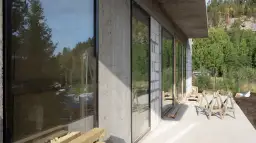 Dom w budowie z dużymi oknami, otoczony lasem. Czy można mieszkać w domu bez odbioru? Tu widać postęp prac.
