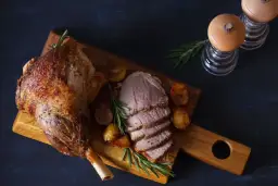 Pieczona jagnięcina z ziemniakami i rozmarynem na desce.