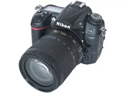 Nikon D7000 z obiektywem 18-105mm VR. Aparat cyfrowy z widocznymi przyciskami i pokrętłem trybów. Dane techniczne tego modelu są imponujące.