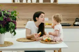 Mama karmiąca dziecko owocami, planując jadłospis matki karmiącej w pierwszym miesiącu.