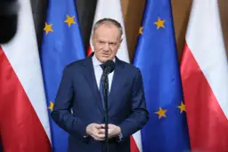 Premier przemawia na tle flag Polski i UE. Sondaże nie dają pewności, czy rząd koalicyjny przetrwa 2026 rok w niezmienionym składzie.