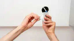 Dłonie montują oprawę lampy sufitowej, przygotowując ją do podłączenia. Widać tu fragmenty przewodów i otwór w suficie, co sugeruje instalację. Pytanie, jakie kołki do lampy sufitowej, jest kluczowe dla stabilnego montażu.