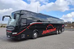 Czarny autokar firmy Eurotrans z czerwonymi pasami i gwiazdami na tle błękitnego nieba.