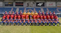 Piast Gliwice zawodnicy w komplecie pozują do zdjęcia drużynowego na tle stadionu.