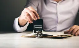 Dłoń z pieczątką nad dokumentami. Zastanawiasz się, ile czasu ma sąd na dostarczenie wyroku w sprawie cywilnej?