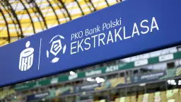 Niebieska tablica z logo PKO Bank Polski i napisem EKSTRAKLASA nad trybunami stadionu. Czekamy na kolejny mecz, kiedy terminarz ekstraklasy.